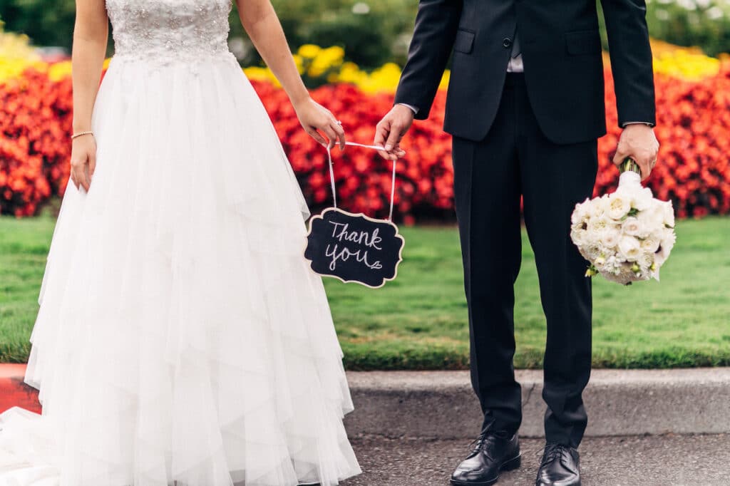 bride and groom holding thank you sign