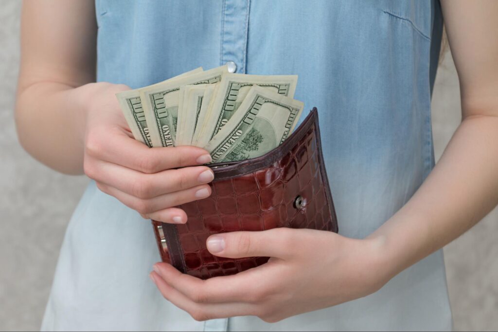 Woman holding wallet with money coming out
