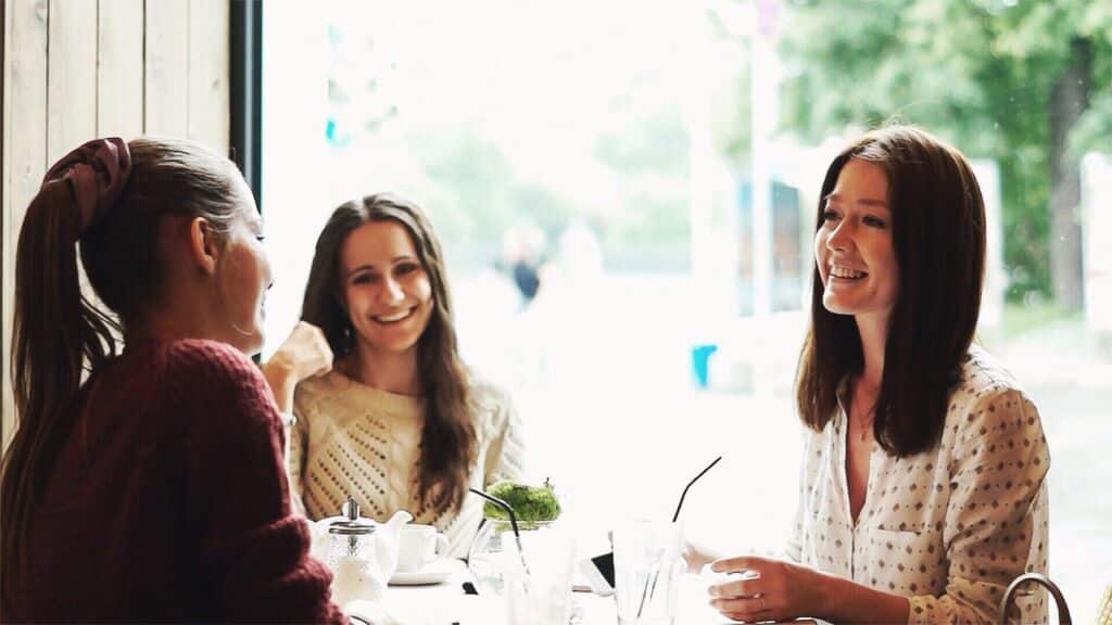 woman talking to two other women laughing