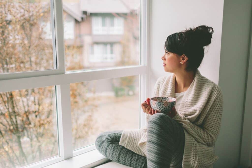 girl relaxing by window with a cup of coffee