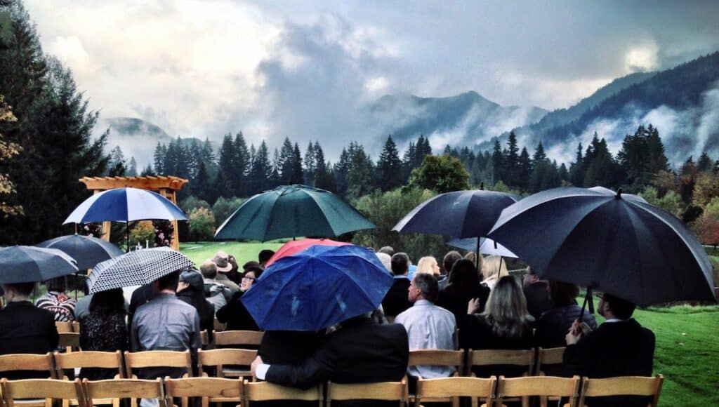 umbrellas with rain at outdoor wedding reception