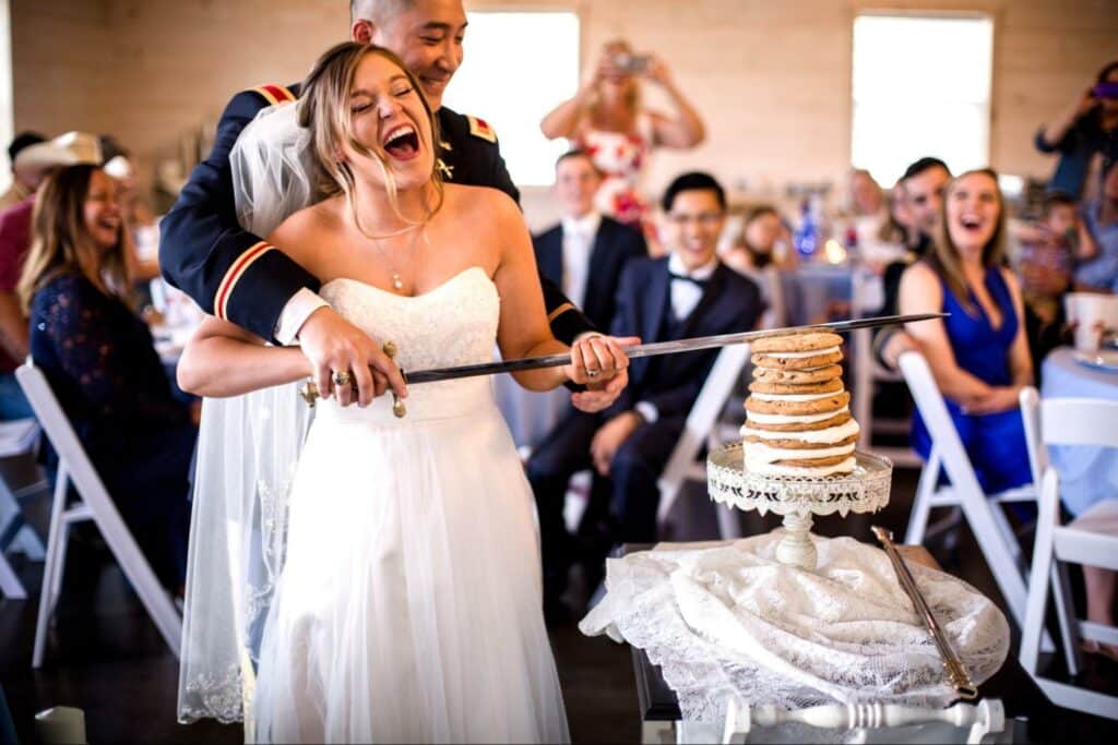 bride and groom using sword to cut wedding cake