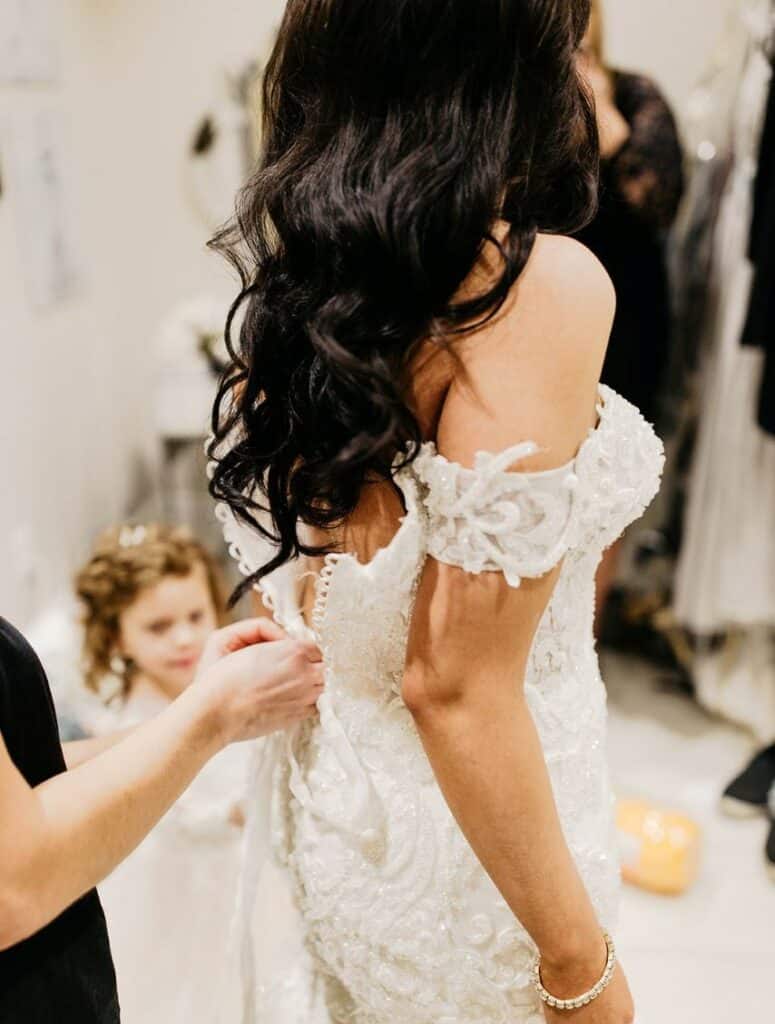 someone zipping up bride's wedding dress