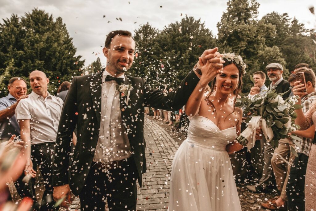 Bride and groom walking through a confetti shower.