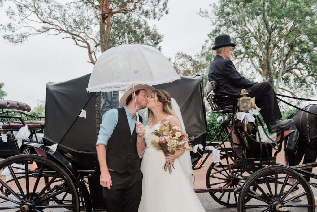 Bride and groom in front of carriage.