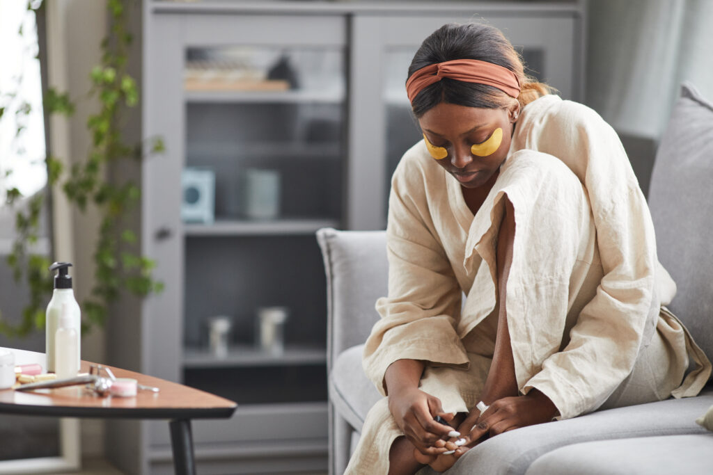 young woman enjoys self care while painting her toenails