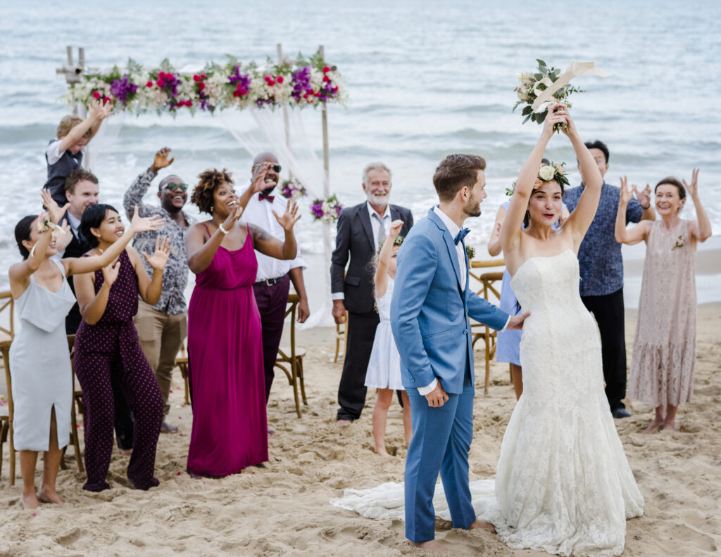 a bride throws her bouquet to the wedding party on the beach
