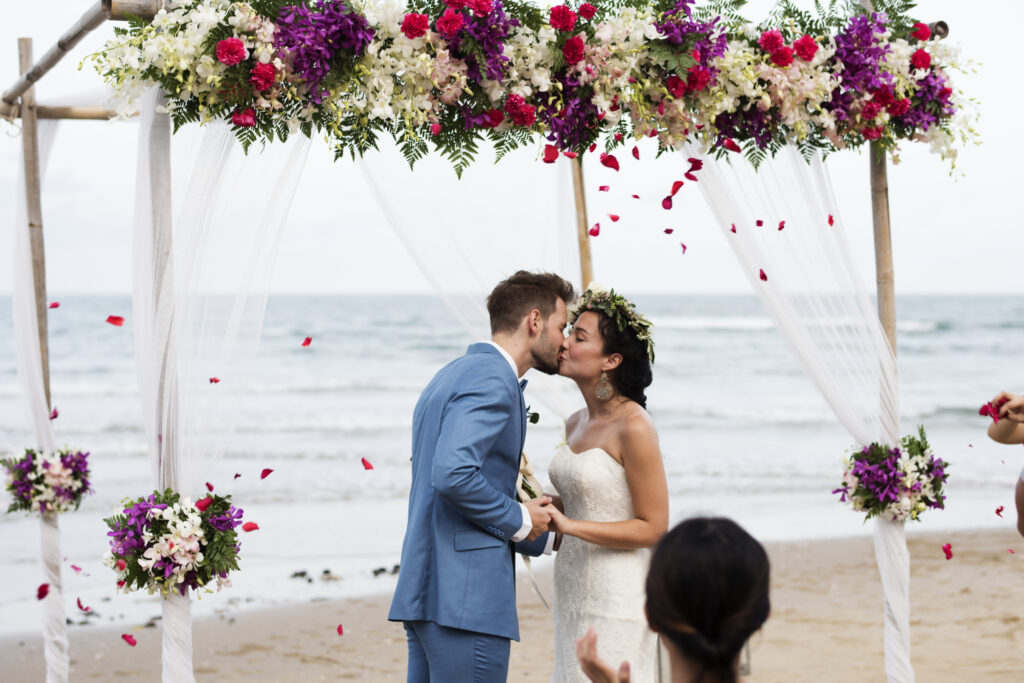 bride and groom kiss at wedding ceremony on the beach