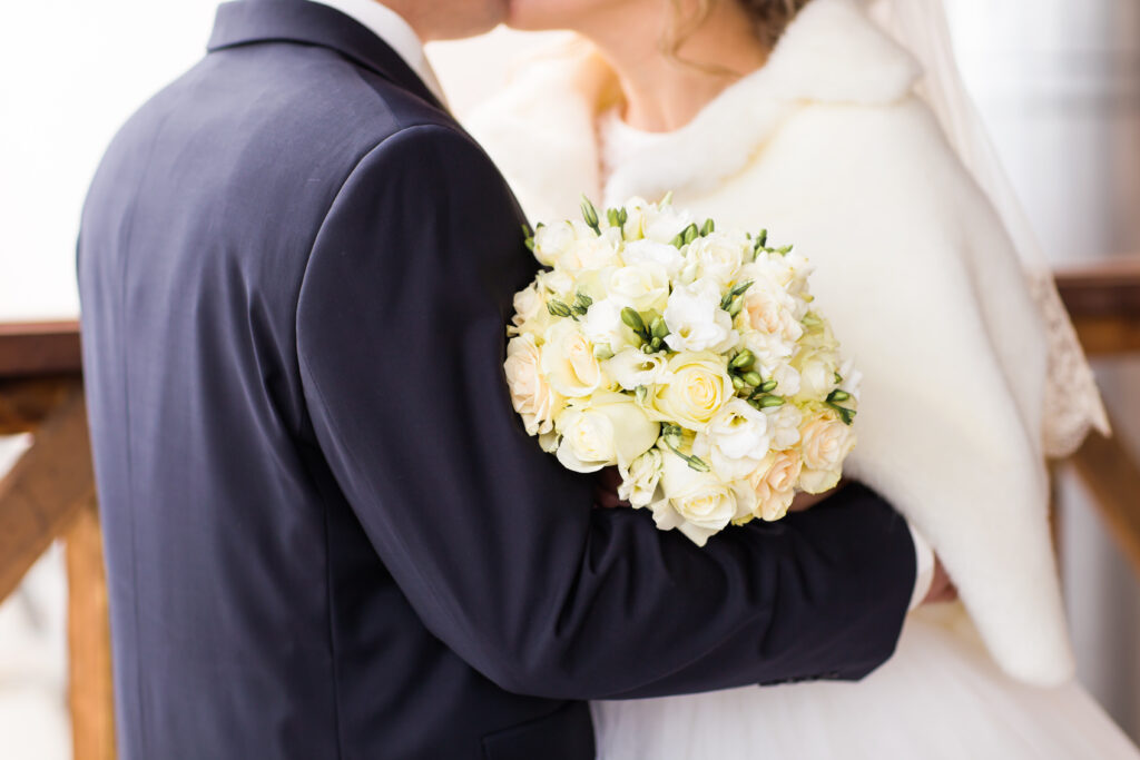 December bride and groom kissing with bouquet