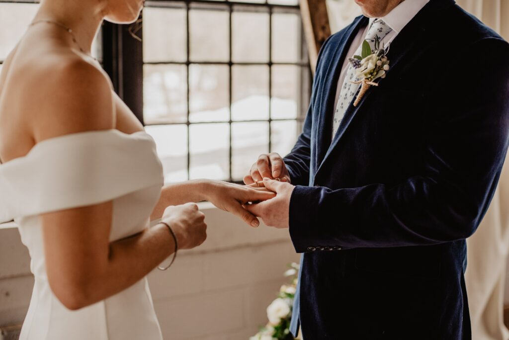 groom placing the ring on the bride's finger