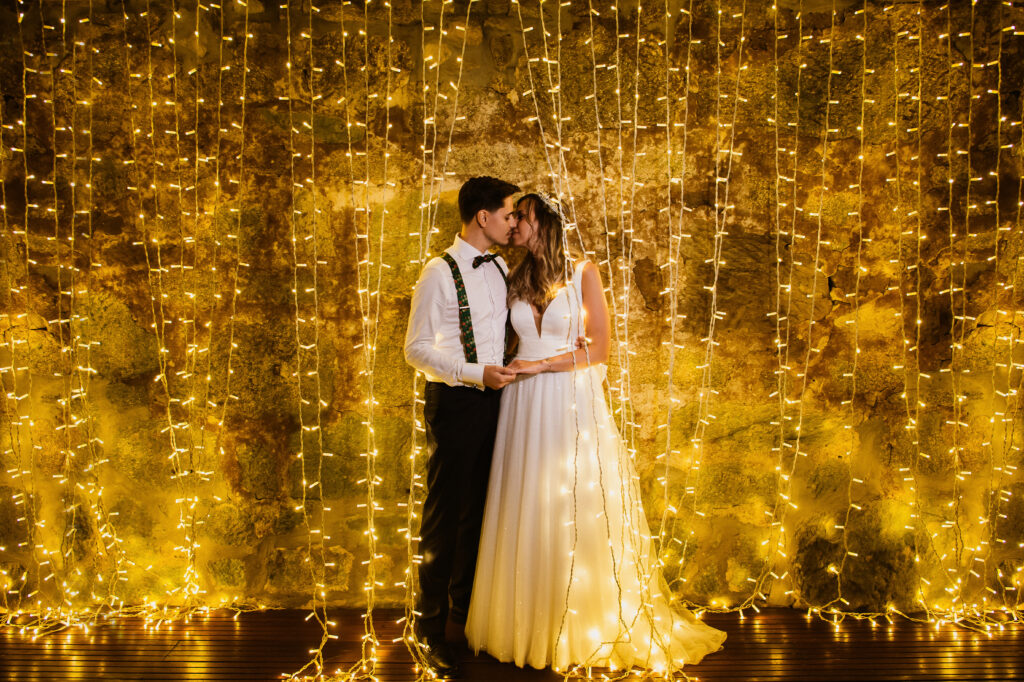 bride and groom kissing in front of golden backdrop