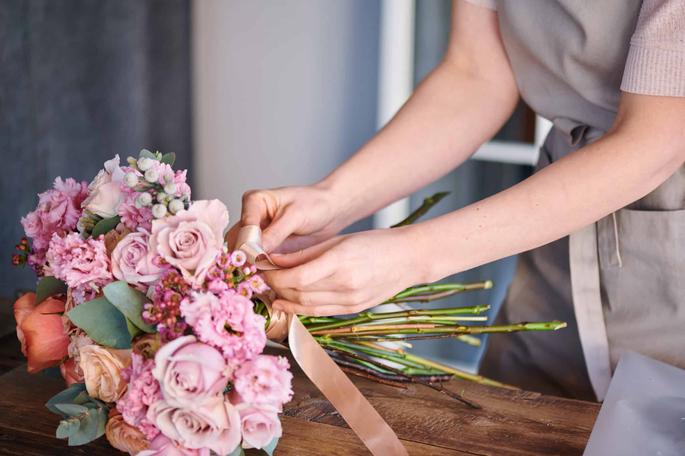 Person tying a ribbon on a wedding bouquet