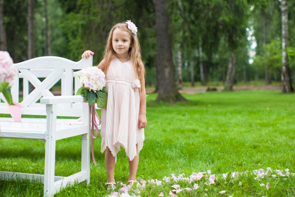 young flower girl standing with a trail of petals behind her