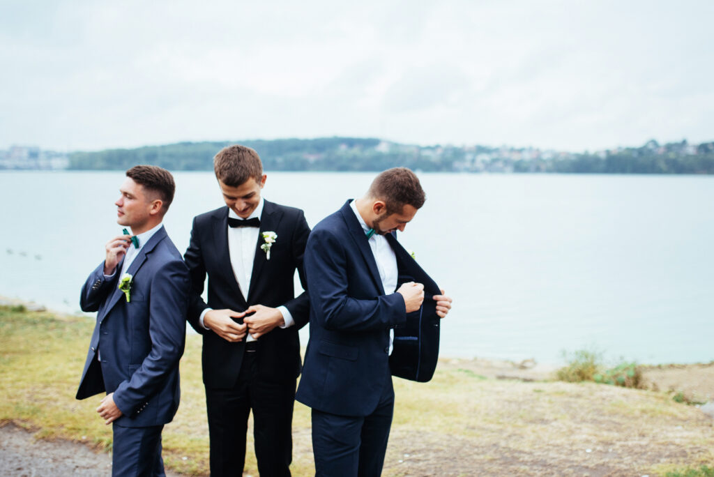 Groom posing with two groomsmen at lake