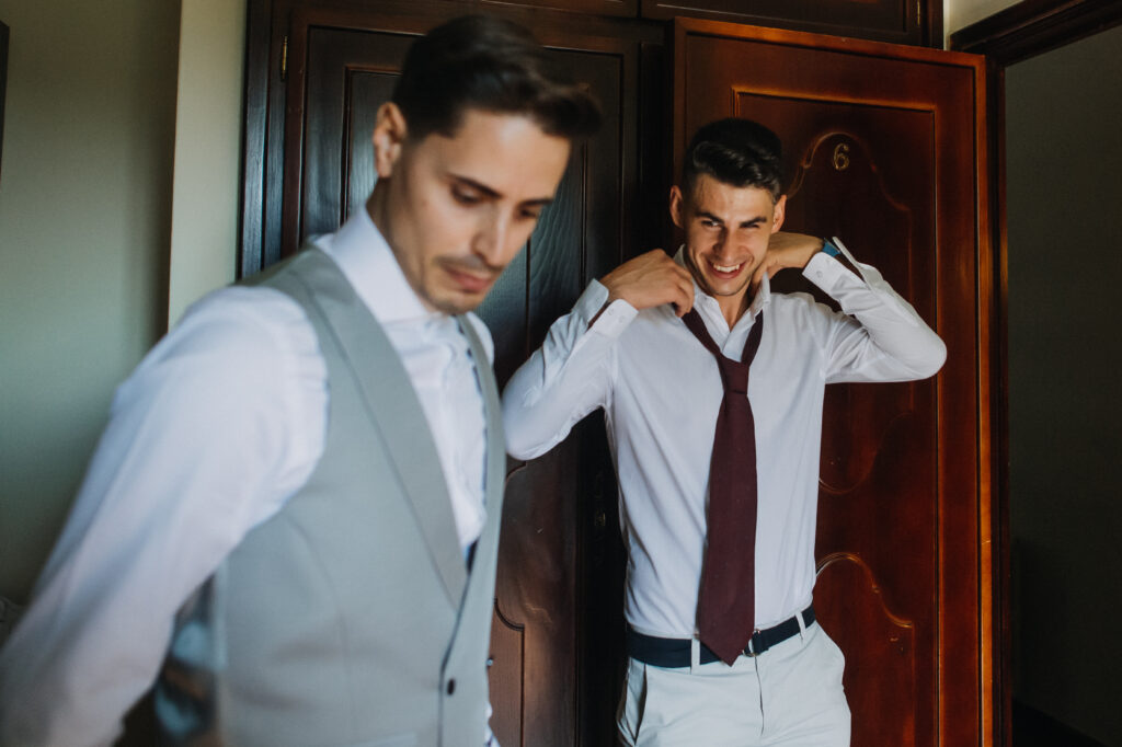 Groom and best man putting on the suit before the wedding