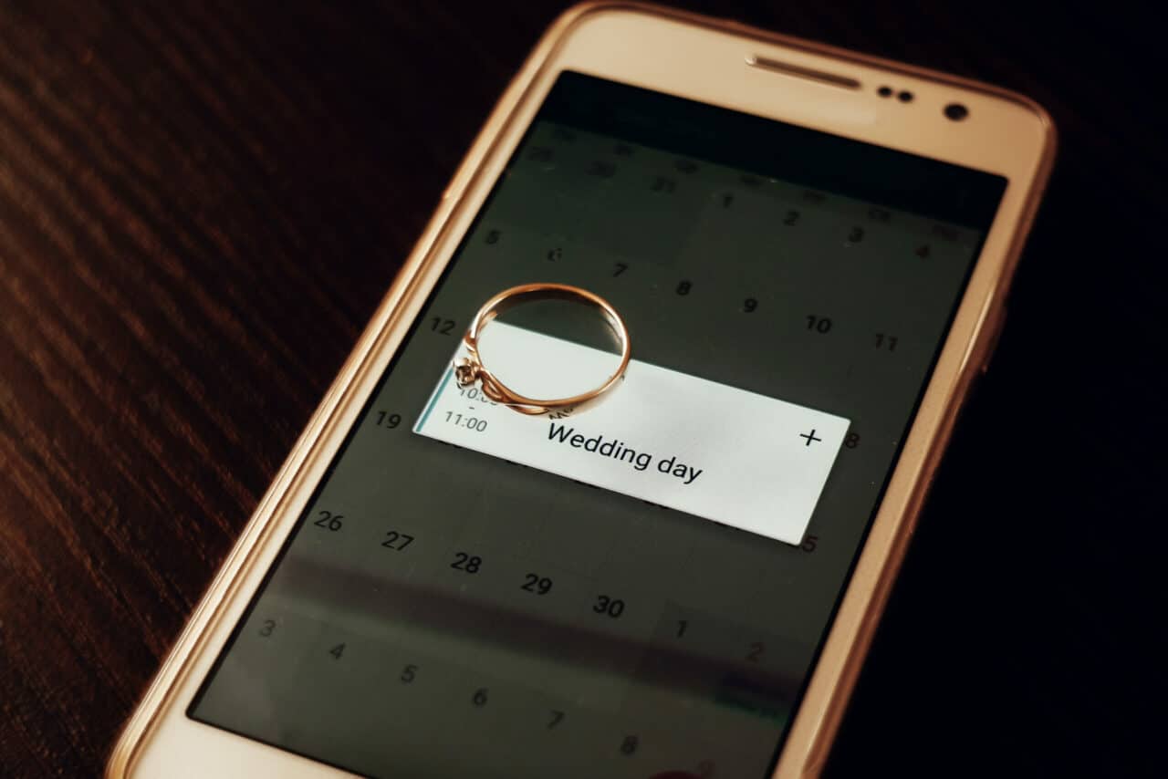 golden engagement ring on phone with calendar with wedding day