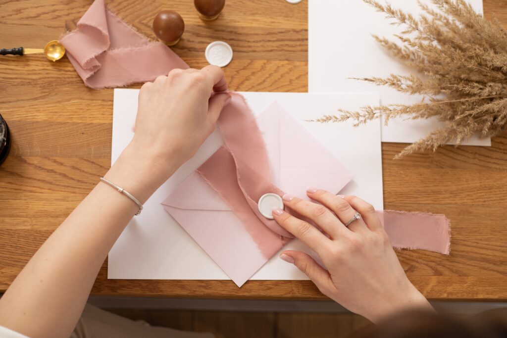 woman prepares pink wedding invitations