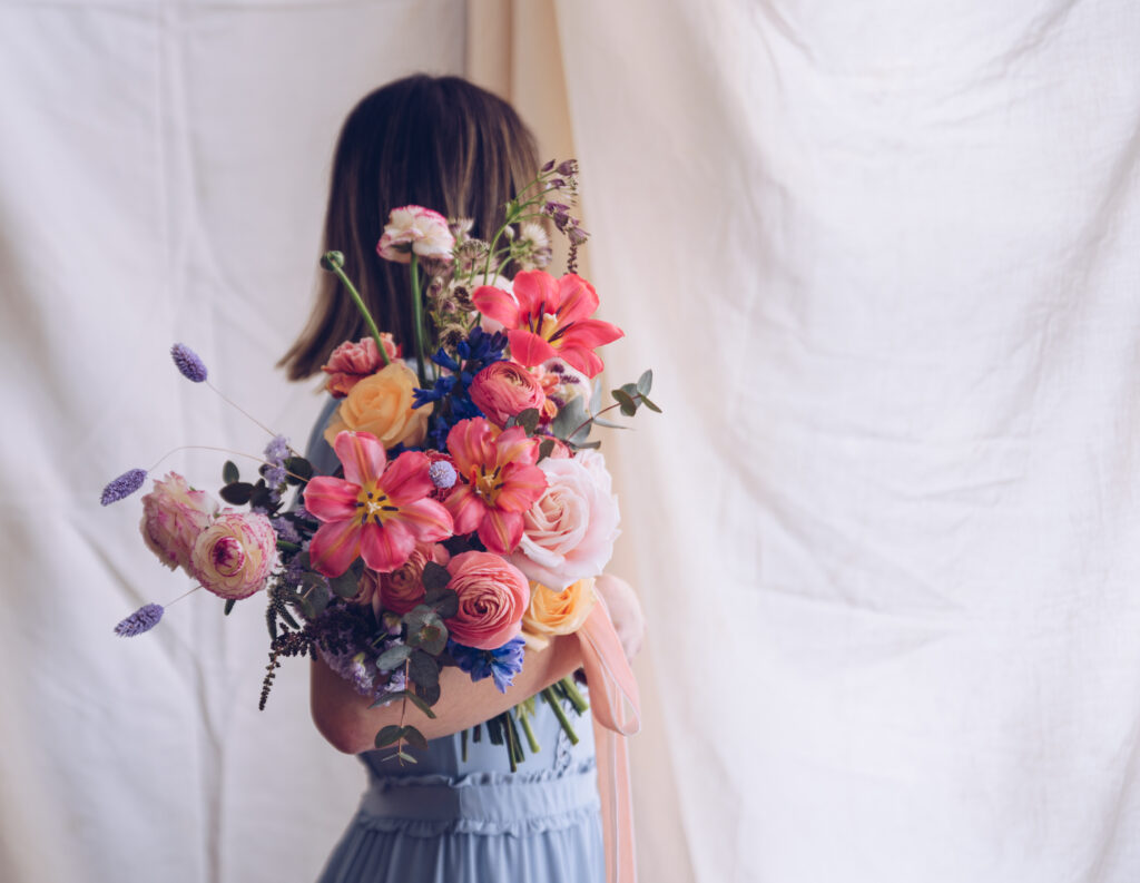 Young woman in a light blue dress holding a bouquet of flowers.