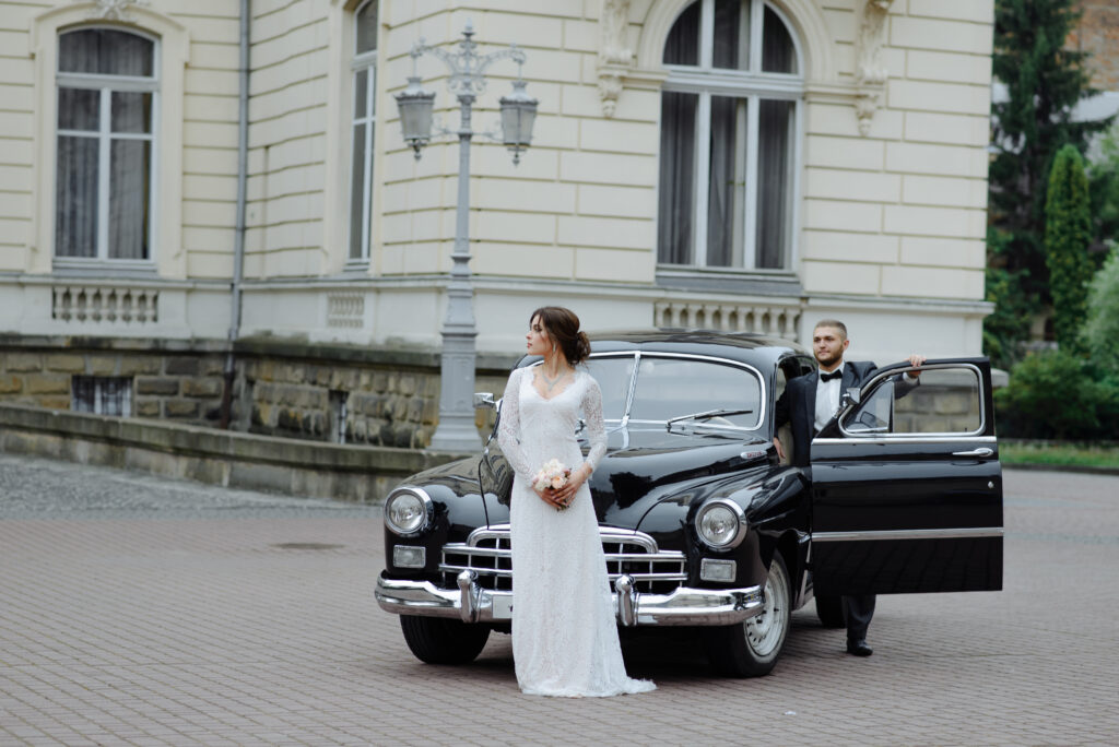 Bride and groom posing with retro car