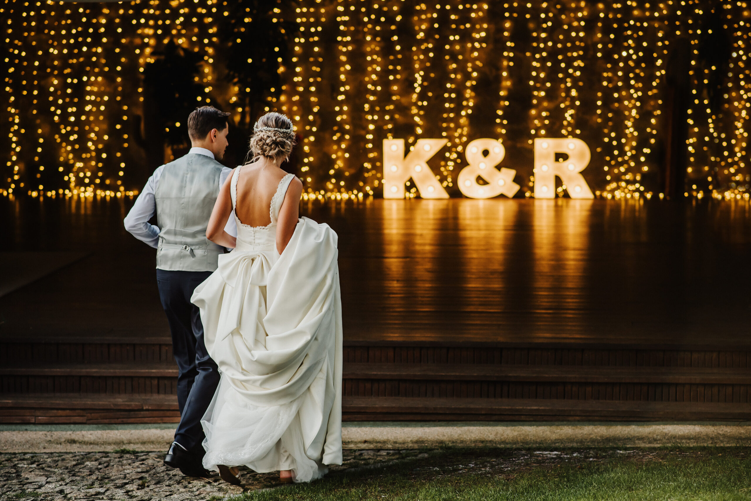 Young couple at their wedding walking towards a reception full of lights