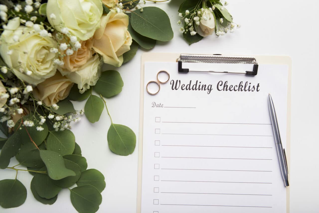 Simple wedding planning checklist with roses and rings on white background