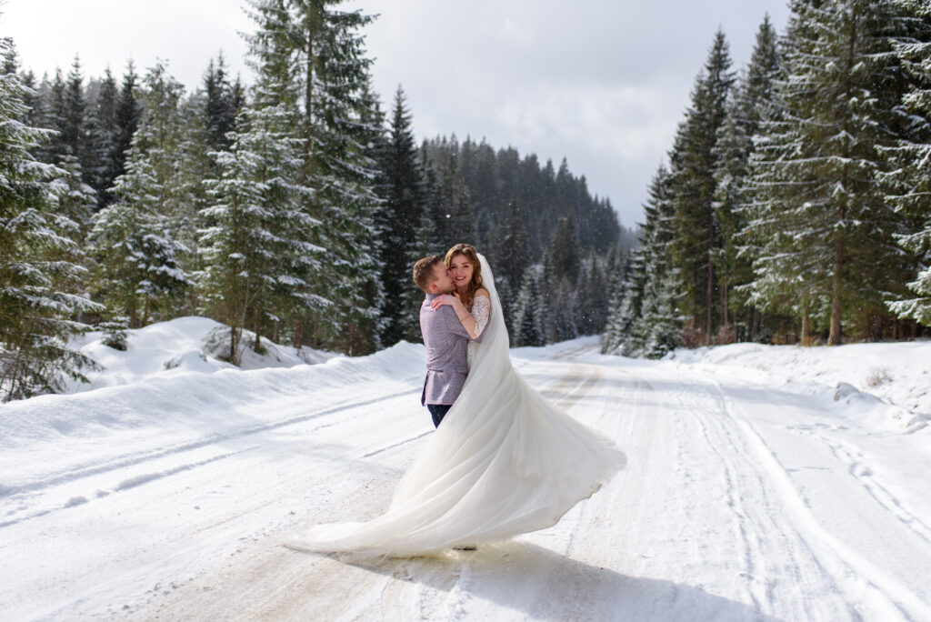 Groom holding bride on a snowy path