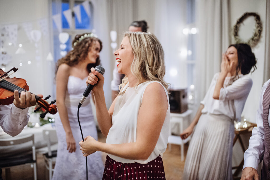 young woman laughing into microphone at wedding