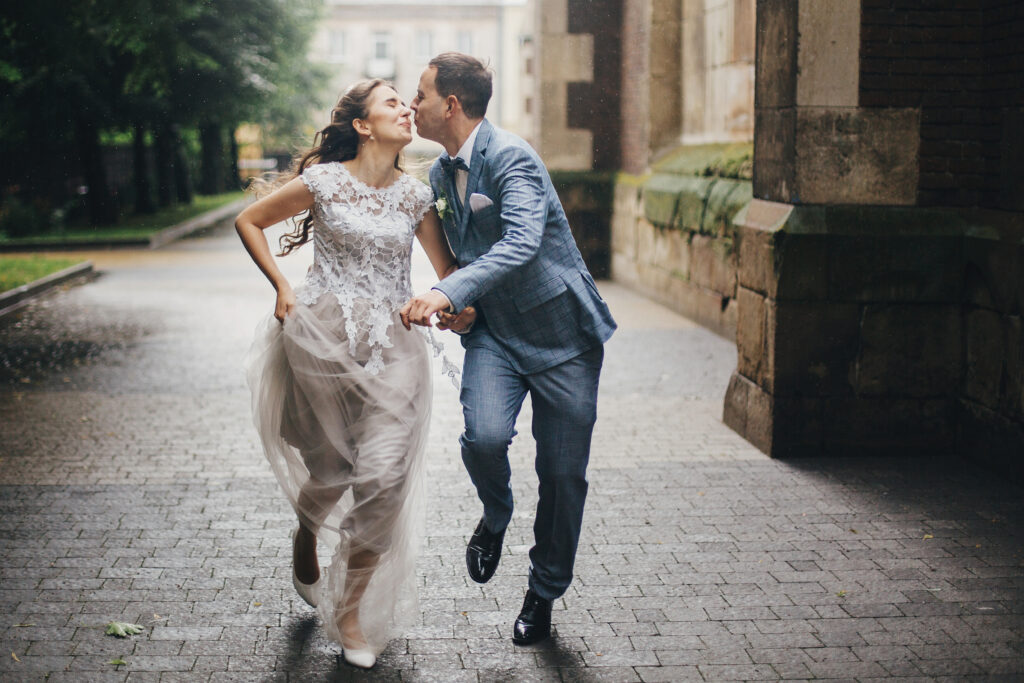 wedding couple running and trying to kiss