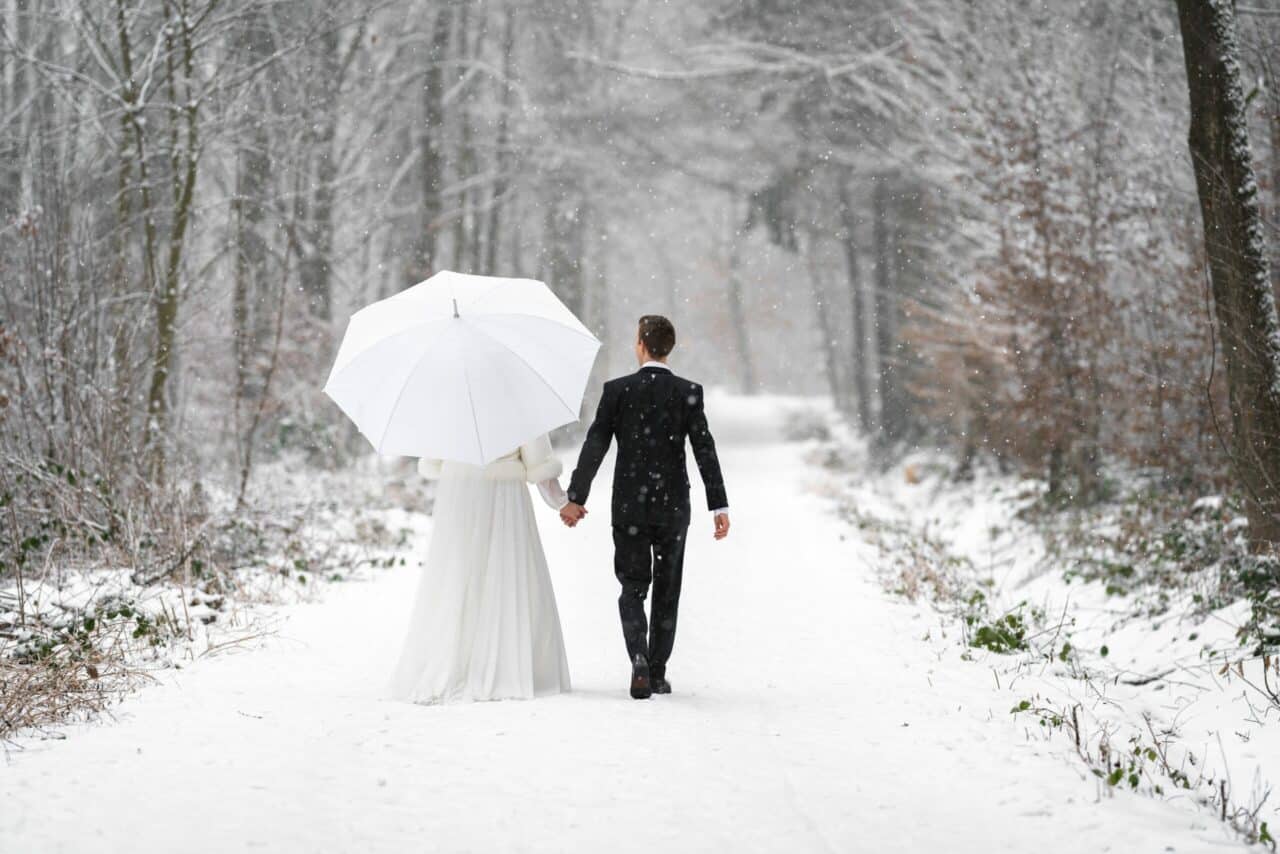 newlyweds walking in the snowy woods for winter wedding