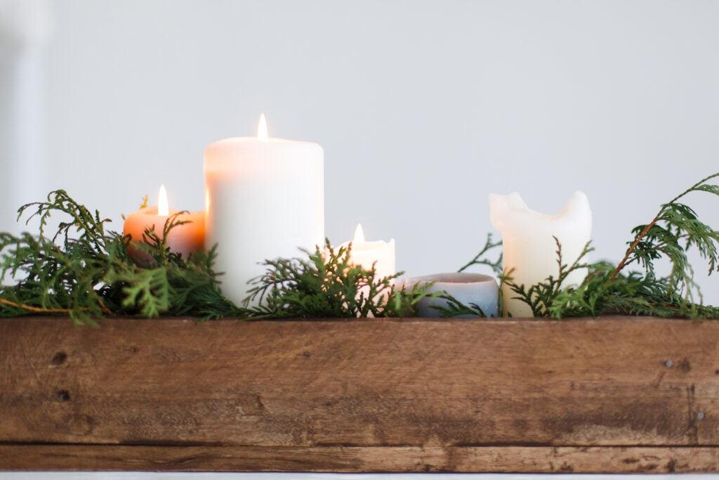 Burning candles in rustic wooden box with cedar branches