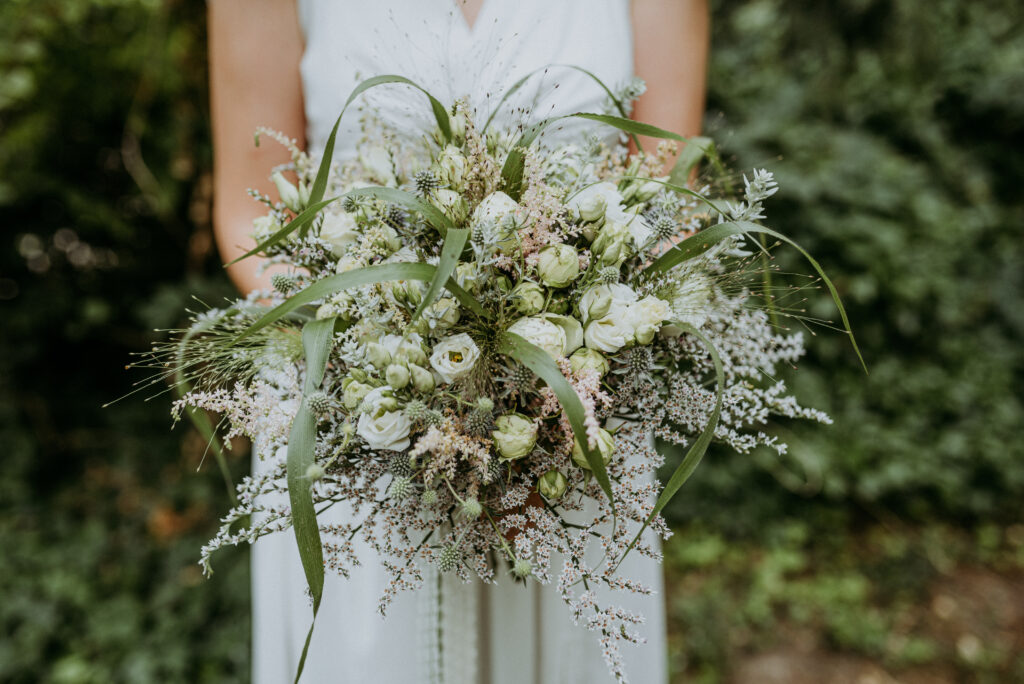 bride holding white and green bouquet