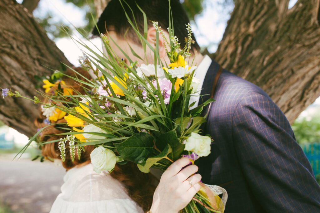 bride and groom kissing behind spring wedding bouquet