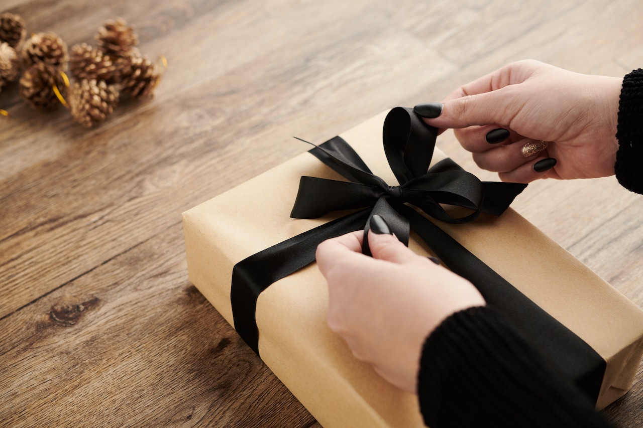 woman tying a black bow on a present