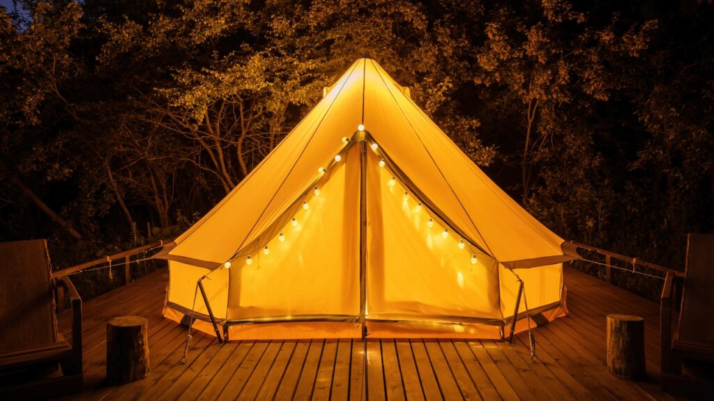 glamping at night glowing tent with chairs