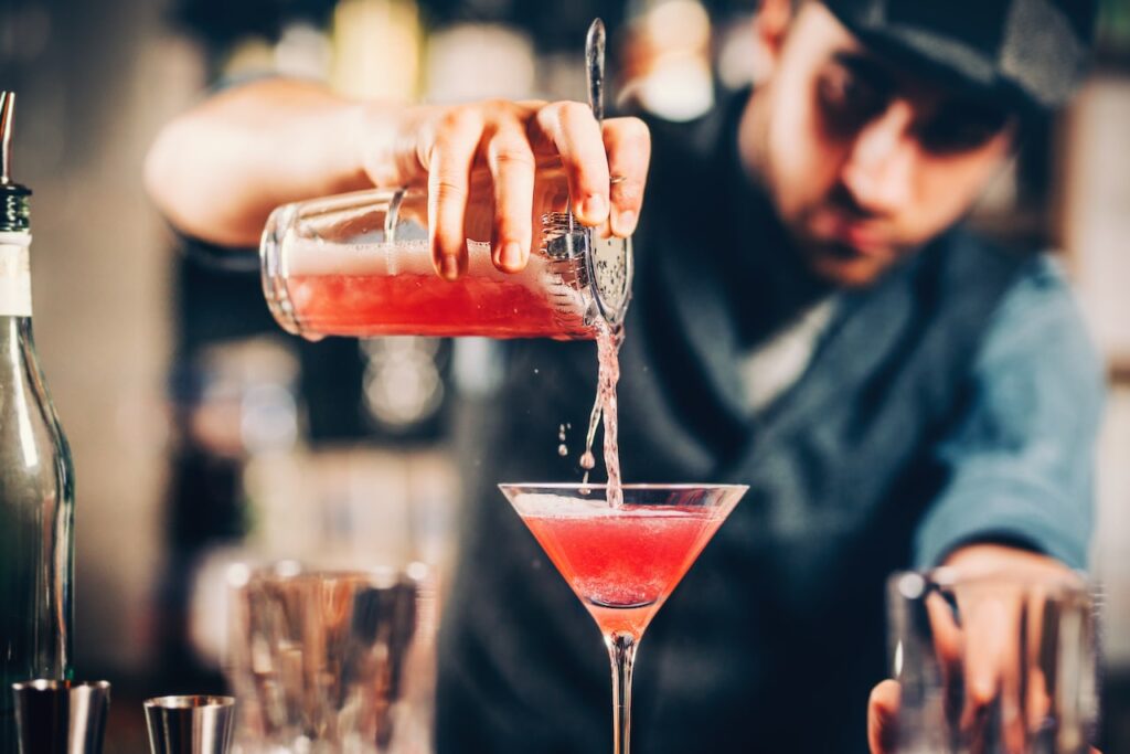 barman preparing and pouring red cocktail