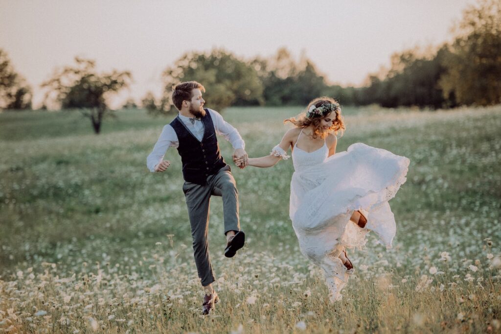beautiful bride and groom running in field