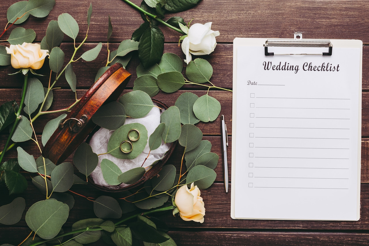 wedding rings and paper planning checklist on wood