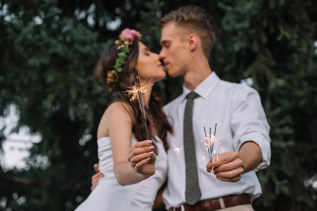 young wedding couple kissing and holding sparklers