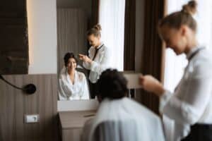 make up artist helping bride get ready for wedding ceremony