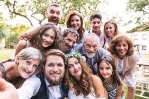 bride and groom with guests taking selfie at wedding reception outside