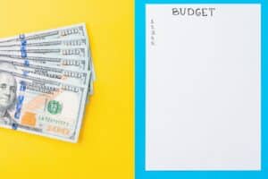 planning budget concept with notepad and hundred dollar bills on yellow and blue background