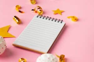 blank notebook surrounded by gold stars on pink background