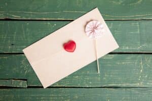envelope with heart seal and small umbrella against green background