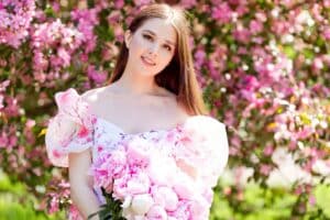 Girl in quinceanera gown holding a large bouquet of pink peonies