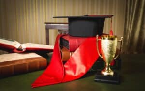 graduation hat, red ribbon and golden cup for first place