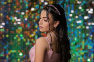 young woman at quinceanera event with green, glittery background