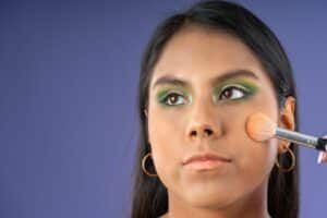 young woman with green colored eye shadow looking away from camera