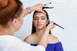 young woman getting bronzer applied before quinceanera