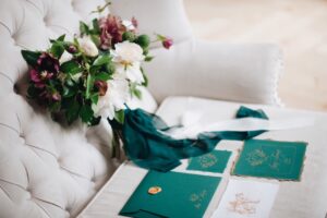 wedding invitations laying on white couch next to flowers