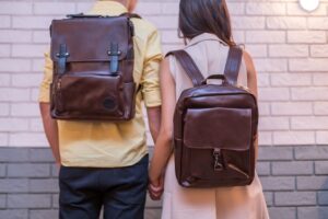 Back of woman and man with brown leather backpacks